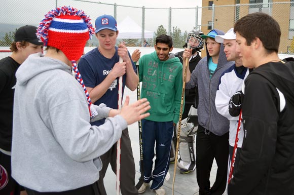 After the games is tied in regulation, RezLetics Road Hockey Tournament organizer Mike van Nostrand, red toque, flips a coin to decide which team will shoot first in a shoot-out while former rep hockey player Tom Menard, far right, looks on.