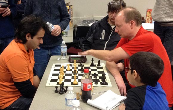 Jose Yunier Bello Cruz (left) plays Graham Swett in the final match of the tournament as fellow competitors look on.
