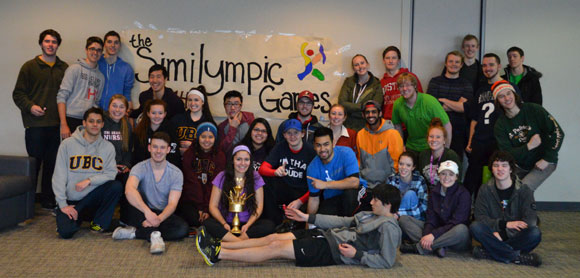 Inaugural Similympics competitors pose for a group shot while Team Purple shows off their gold-looking trophy.