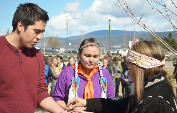 At the Tree Planting Ceremony on March 21, Westbank First Nation Elder Delphine Derickson passes out tobacco to Hailey Causton and fellow Okanagan Nation member Nicholas Clark to place in the ground underneath the tree.