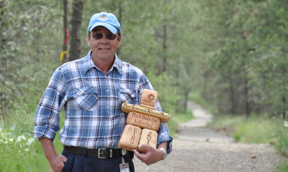 Allan King, former manager of maintenance and grounds, with the City of Kelowna's Most Environmentally Dedicated Individual award he won in 2010. Behind him is the campus trail system, one of the many campus sustainability initiatives King has championed over the years. 