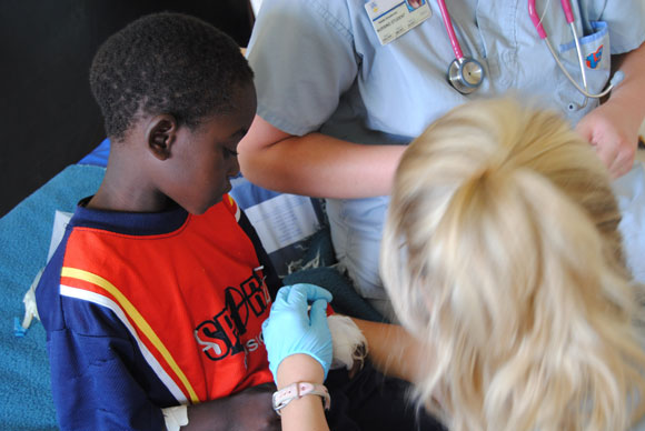 School of Nursing students do a painful dressing change on a young Zambian boy at Lewanika General Hospital in Zambia during a 2012 practicum. There were no pain medications to give to their patient.