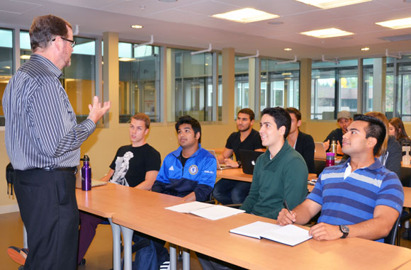 Management professor John Burton recently moved students Mark Brandle, Samin Mahmood, Michael Flaherty-Specht and David Rogas to the front row of his classroom as part of the rolling seats initiative. 