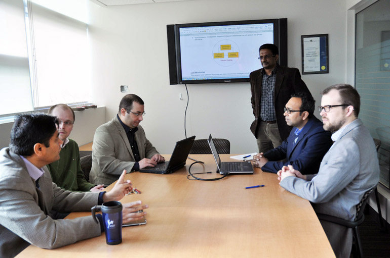 Rehan Sadiq, left, meets with fellow School of Engineering professors, Lukas Bichler, Ahmad Rteil, Kasun Hewage, (standing), Shahria Alam, and Joshua Brinkerhoff to discuss the four-year plan for their research project.