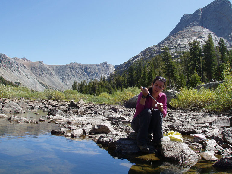 Post-doctoral researcher Janice Brahney takes a water sample at the outlet of Black Joe Lake, Wind River Range, Wyoming to test for phosphorus pollution. 