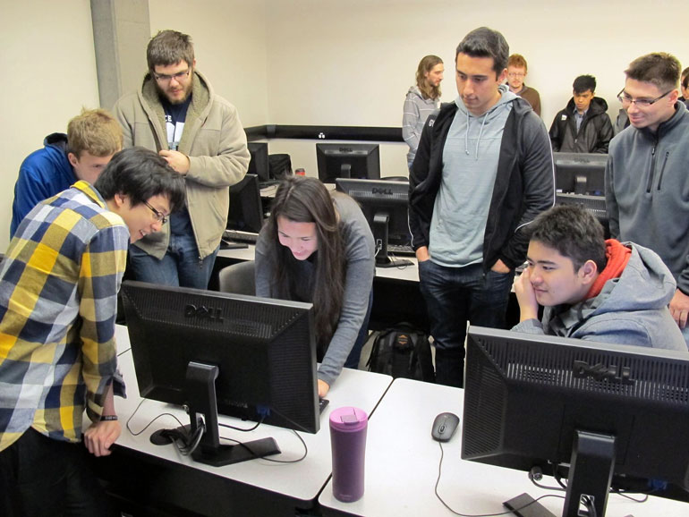 Eric Huang, far left, and Shannon Farvolden (leaning over computer) demonstrate some basic computer skills to students from KSS during UBC Okanagan’s recent Computer Science Day. 
