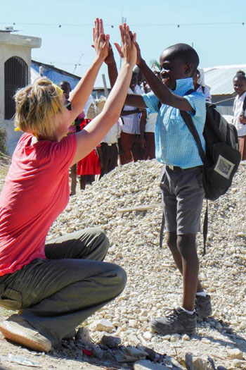 UBC Okanagan Human Kinetics student Paige Marzinzik high fives a young boy during her last visit to Haiti.