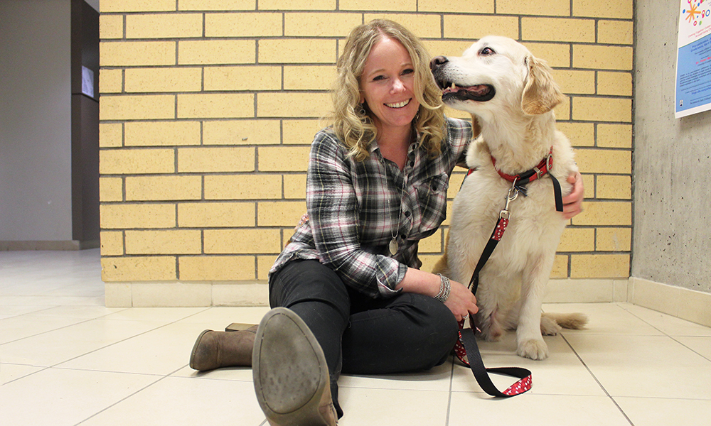 A woman and a golden lab pose for a photo