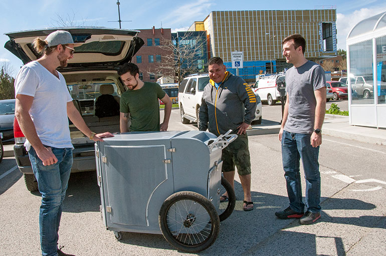UBC grad students Kurt Yesilcimen, second from left, and Connor Keegan, far right, give the cart a final inspection before handing it over to Metro Community Church’s Devon Siebenga and Ramsay Collier.