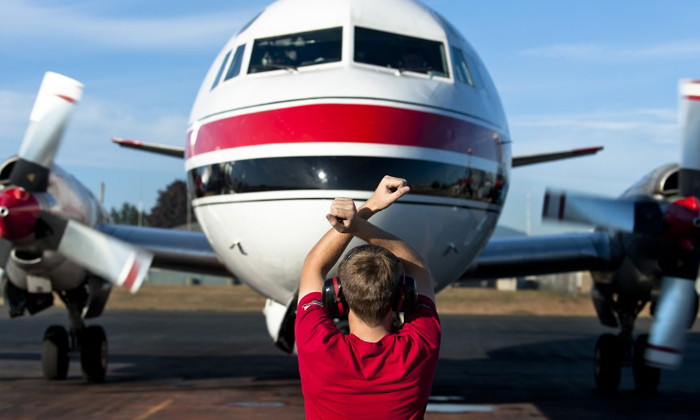 Aircraft marshaller giving direction to a Conair Tanker plane