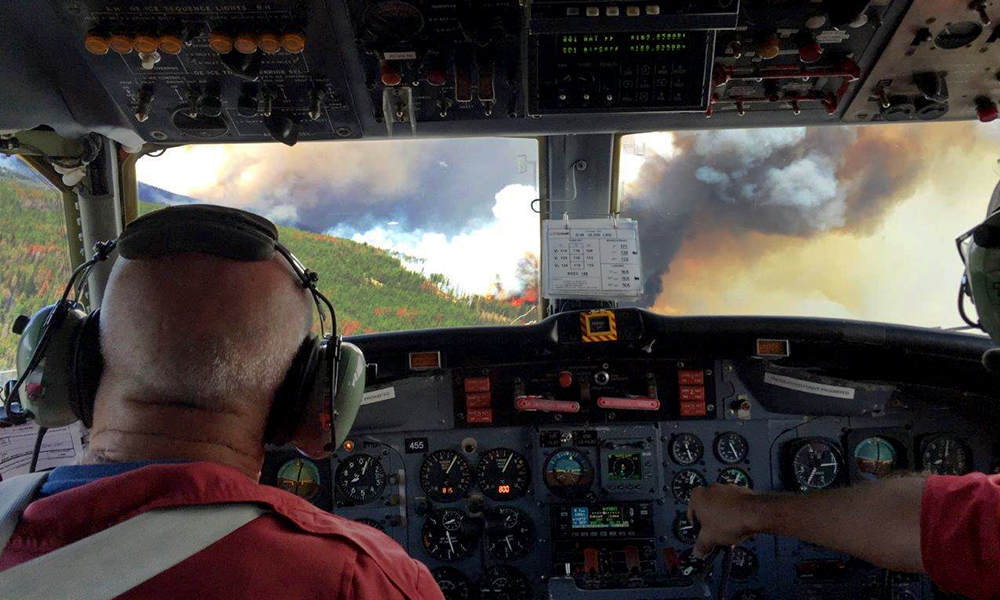 Pilots looking out the cockpit window at a wildfire