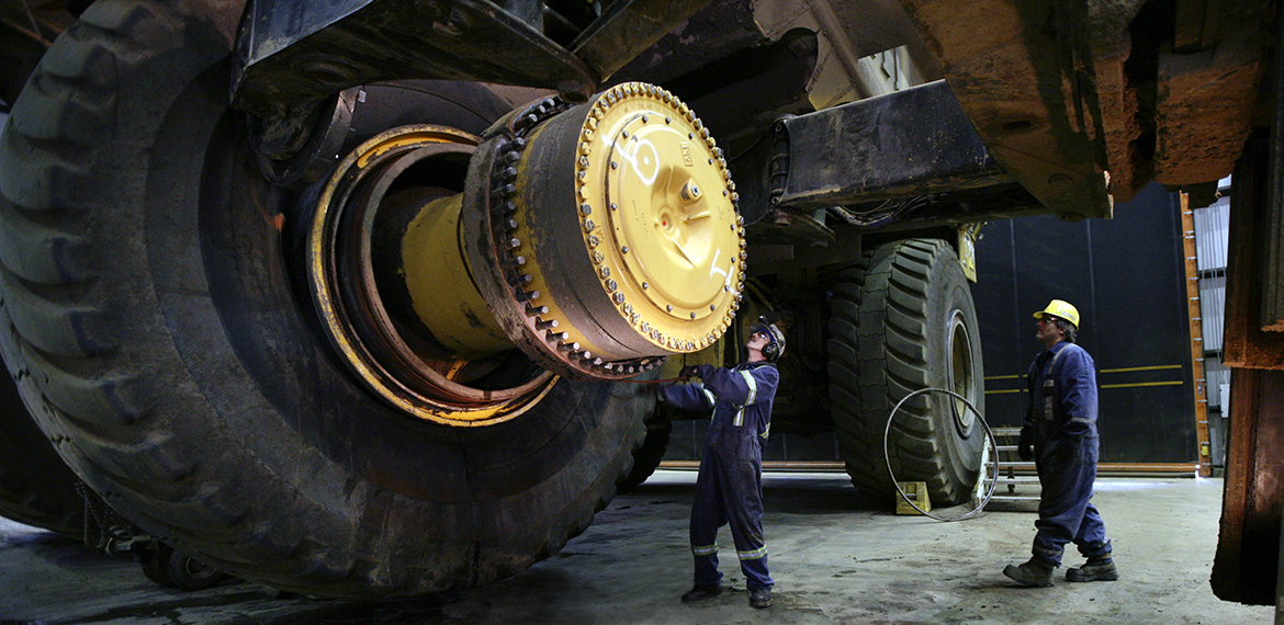 Workers inspecting a large mining truck
