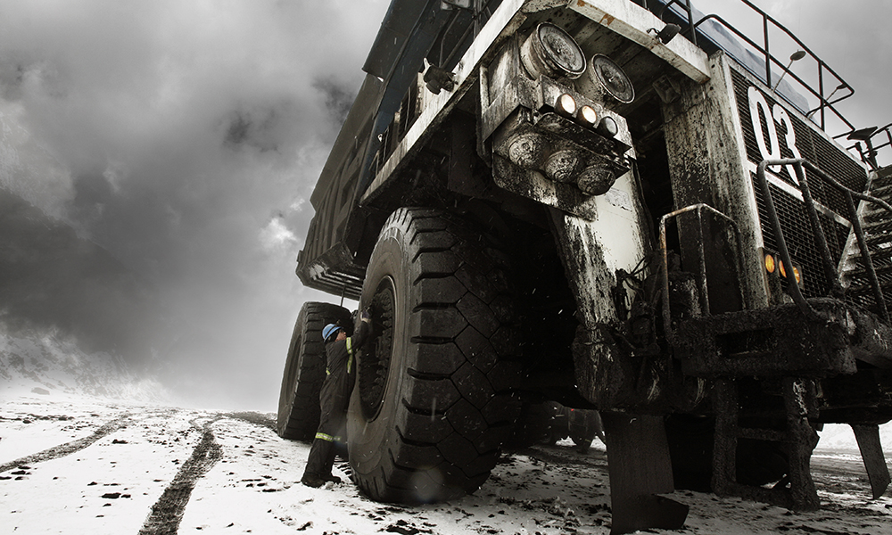Worker maintaining a large mining truck in the snow