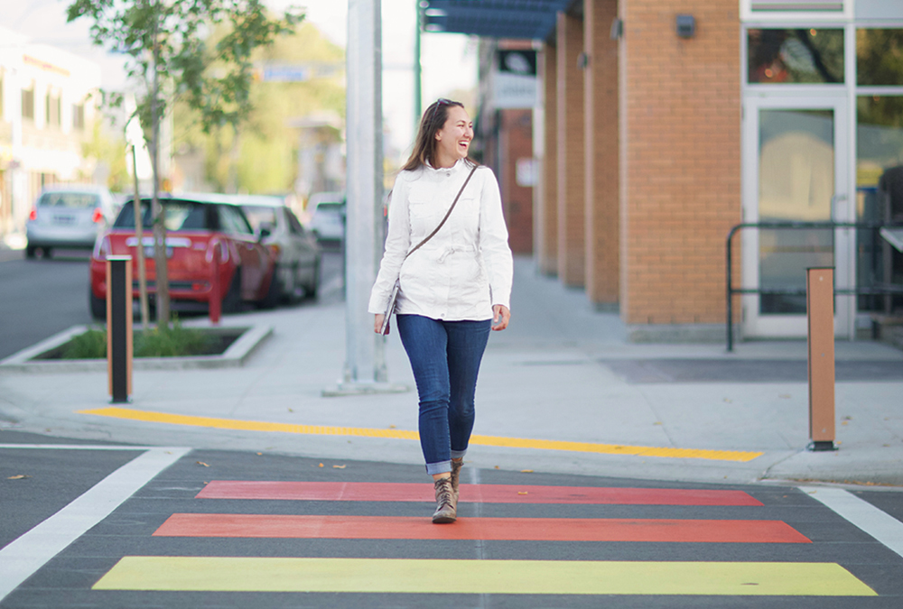 Casey Hamilton walking on a rainbow crosswalk in downtown Kelowna
