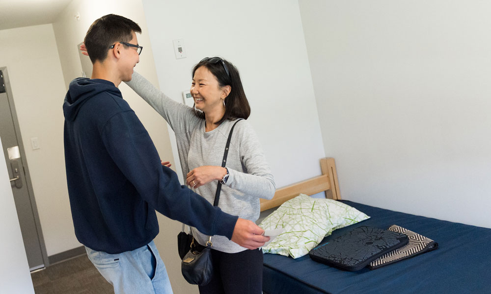 Mother and student hugging in a dorm room