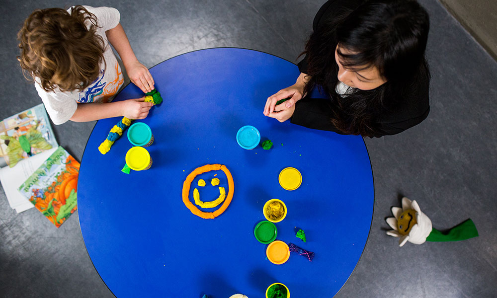 A view from above of a woman and child playing with Play-Doh
