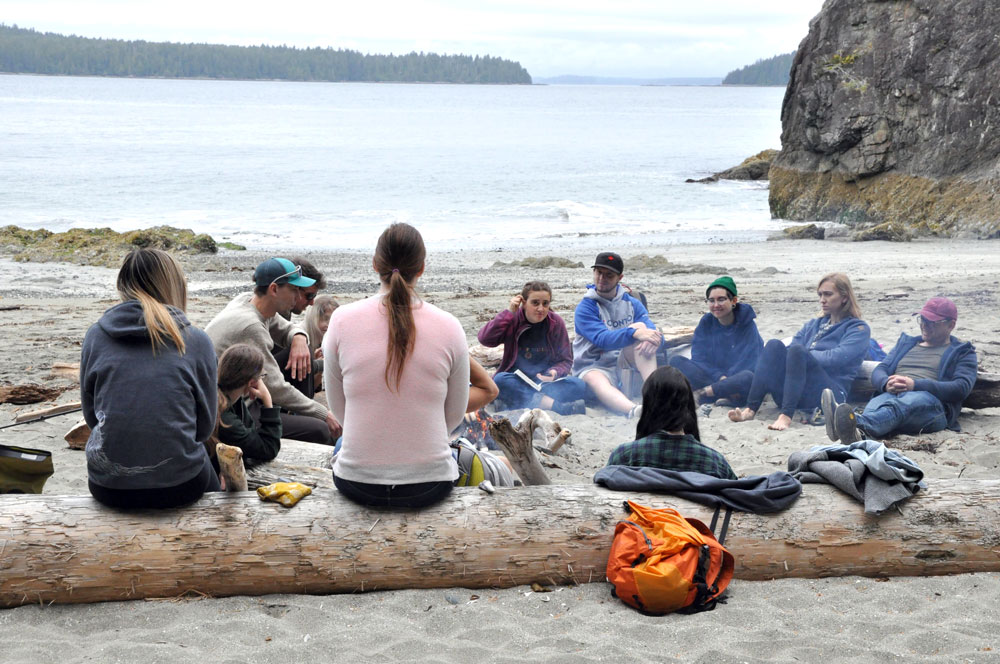 A group of UBCO Humanities students on the beach around a fire