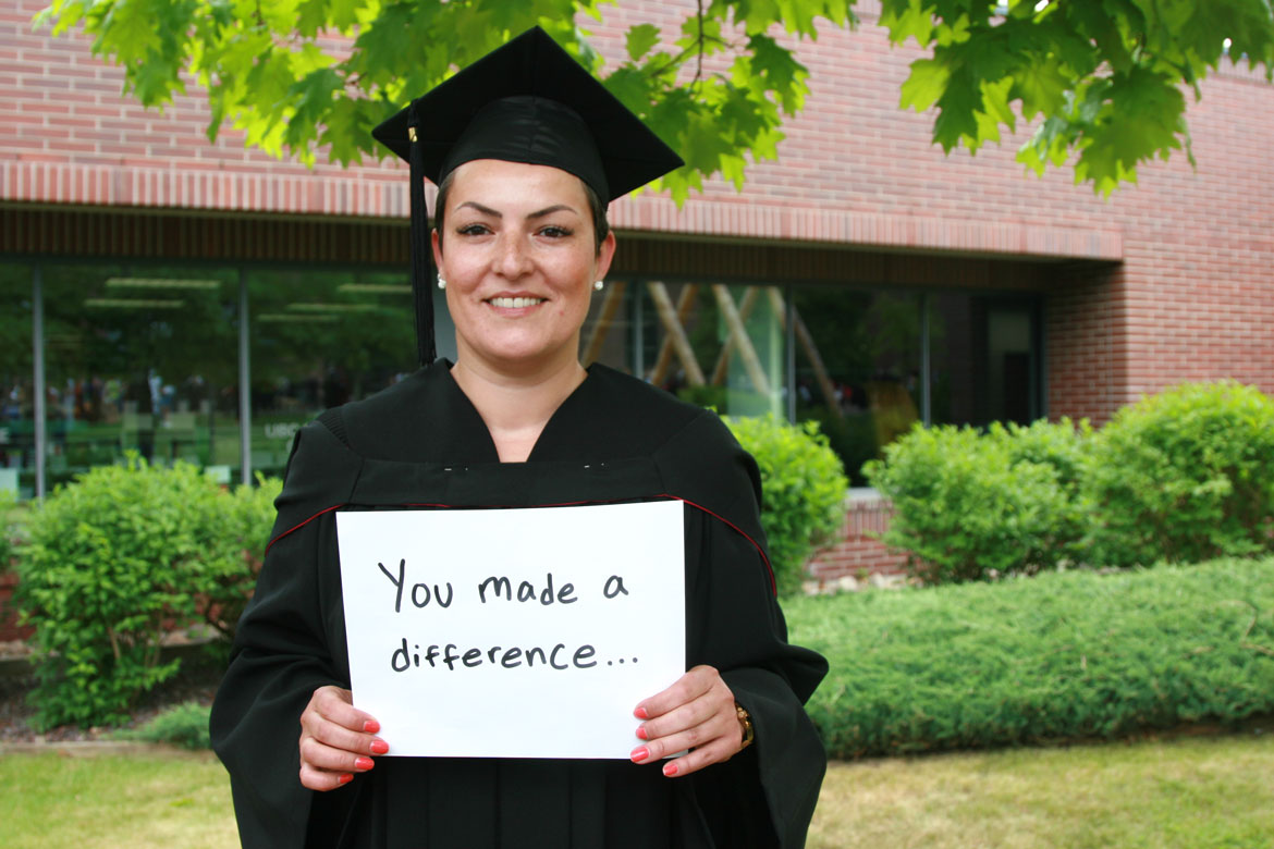 UBCO graduate holding a sign that says "you made a difference..."