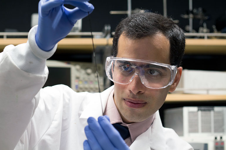UBC doctoral student Hossein Montazerian takes a close look at a tiny sensor embedded into a fibre. 