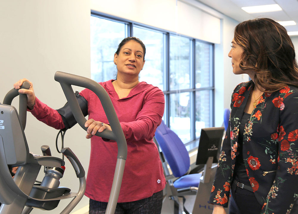Mary Jung talking with a woman on an elliptical machine