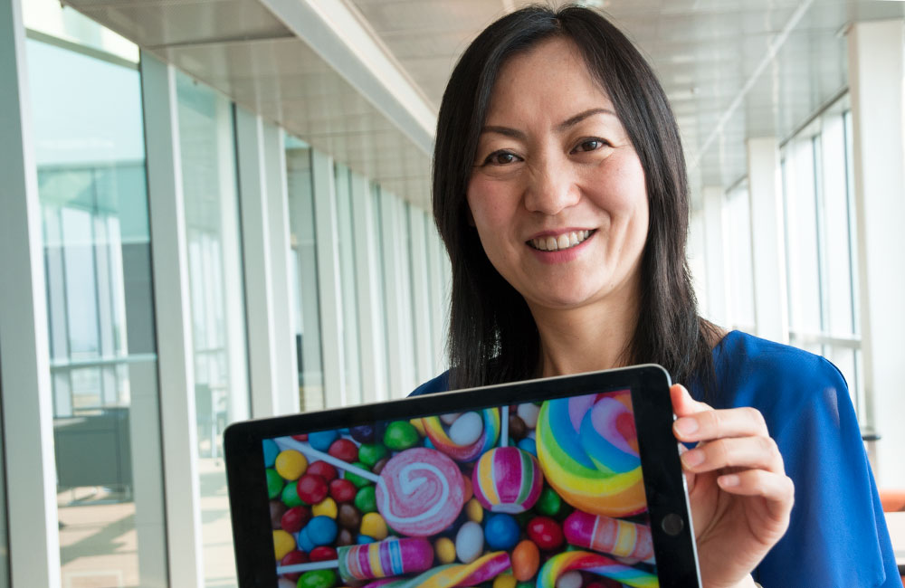 Ying Zhu holding up a tablet picturing various candy