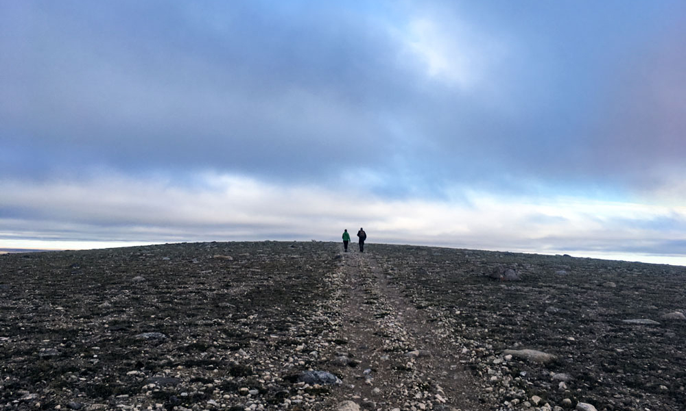 Landscape view of researchers walking across a rocky plane in Nunavut.