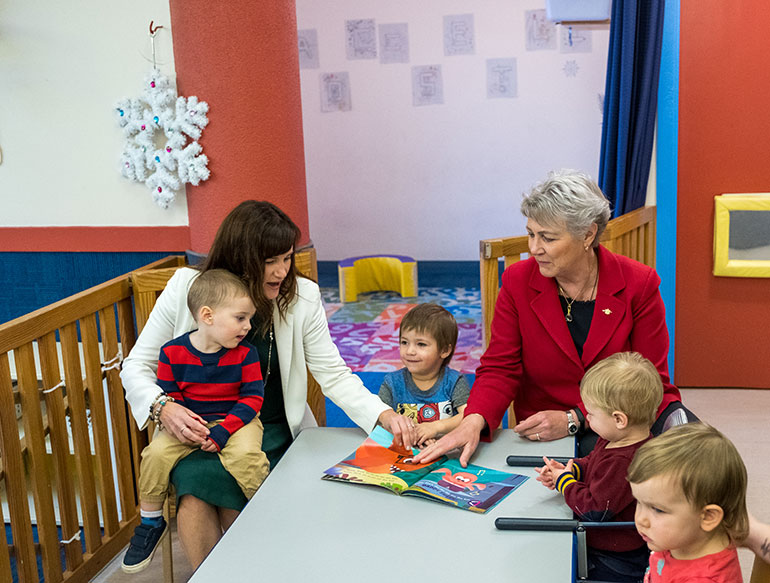 UBCO Professor Lesley Lutes, president of the Learning Centre’s board of directors, (left) holds Eli while she reads a story with Katrine Conroy, Minister of Children and Family Development to Lucas, Tyler and Amelia.