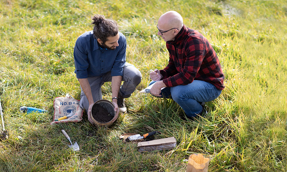 Men on ground surrounded by soil and tools
