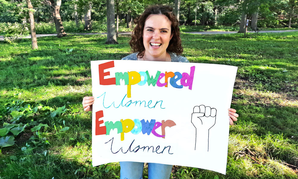 Tayana holding a sign: Empowered women empower women