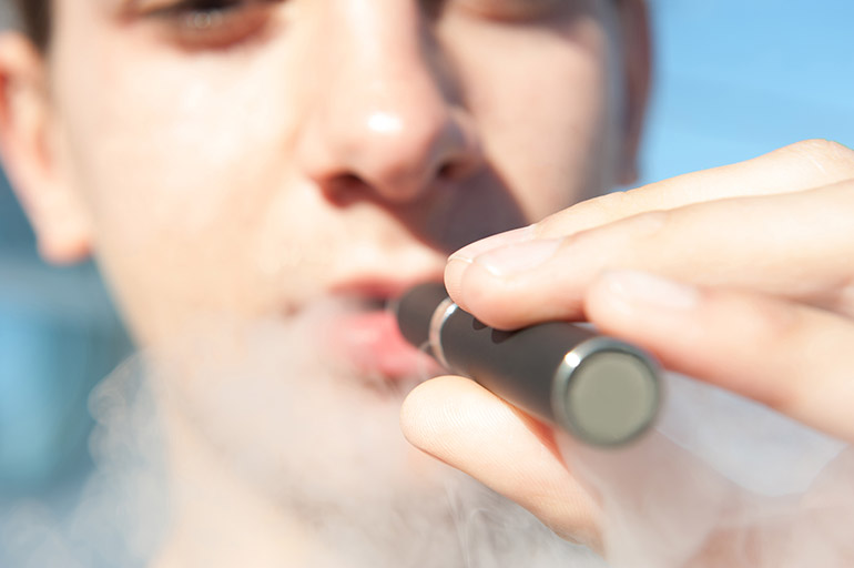 A young person vaping an e-cigarette.