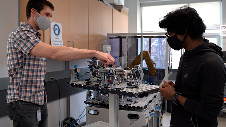 Assistant Professor of Teaching Dean Richert and student Ram Dershan prepare a workstation that will be used for the industrial automation micro-credential course.