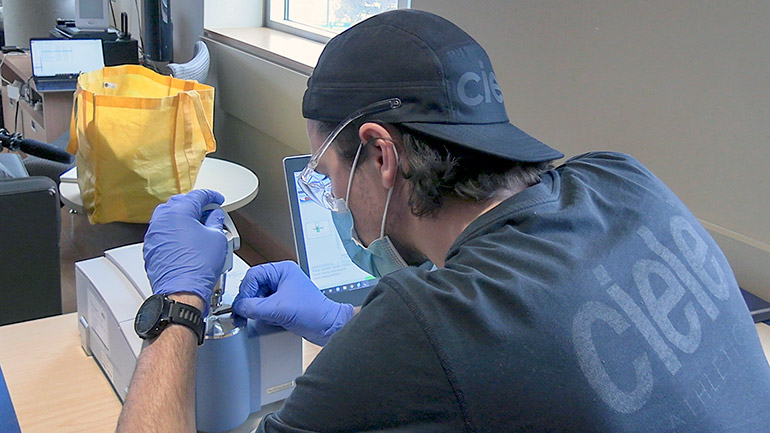 Third-year UBCO nursing student Thomas Pool, a trained FTIR technician, checks a drug sample during a harm-reduction session on campus.