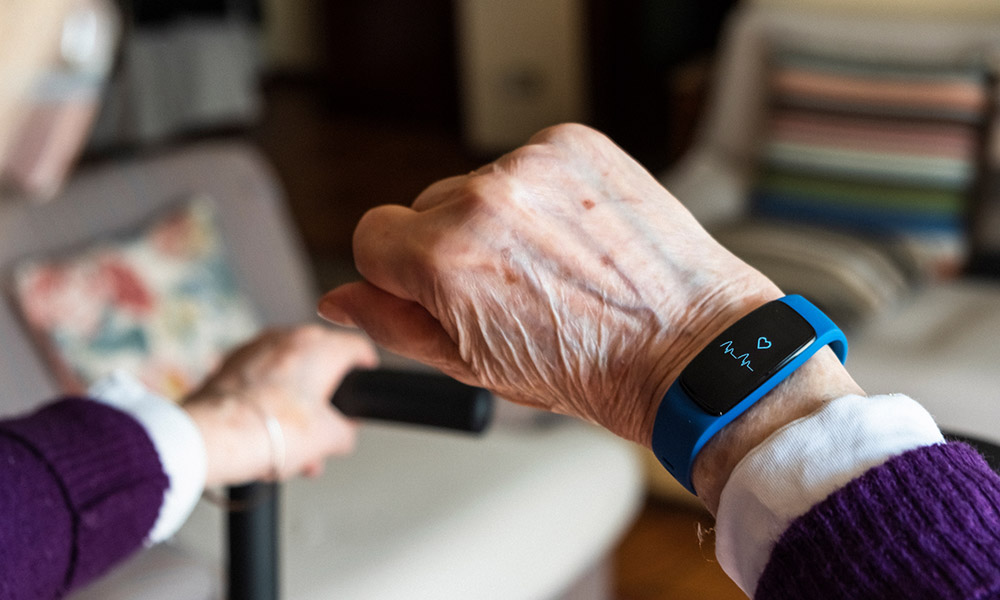 an elderly person holding up a piece of wearable tech