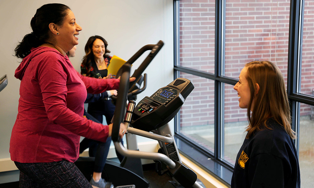 A photo of a person on a treadmill and a student helper