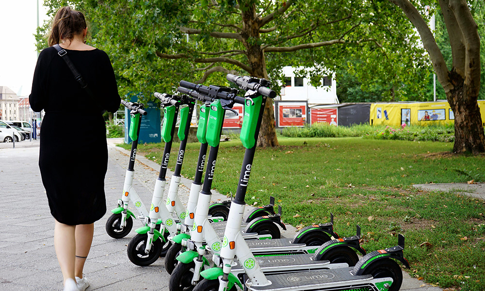 A photo of a woman walking along a row of e-scooters