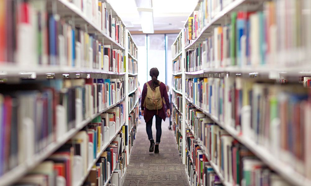 A girl walking amidst library stacks