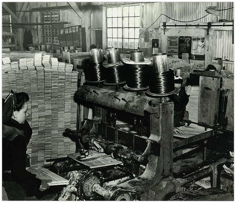 Two women operating a box factory machine.