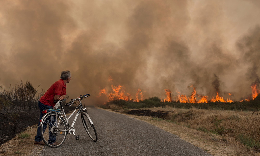 A photo of a man cycling near a wildfire