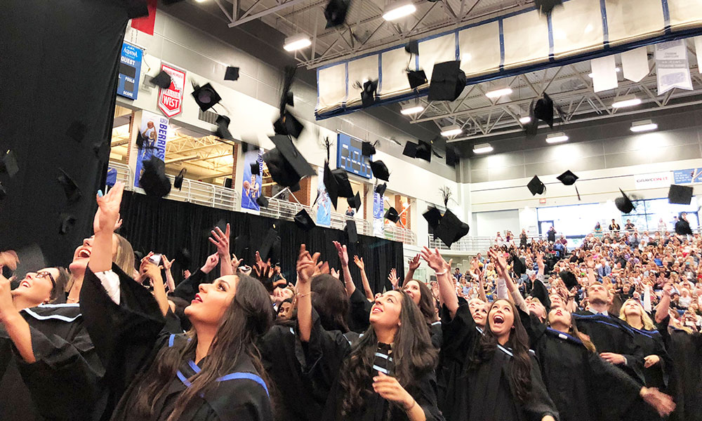 A photo of graduating students throwing their hats