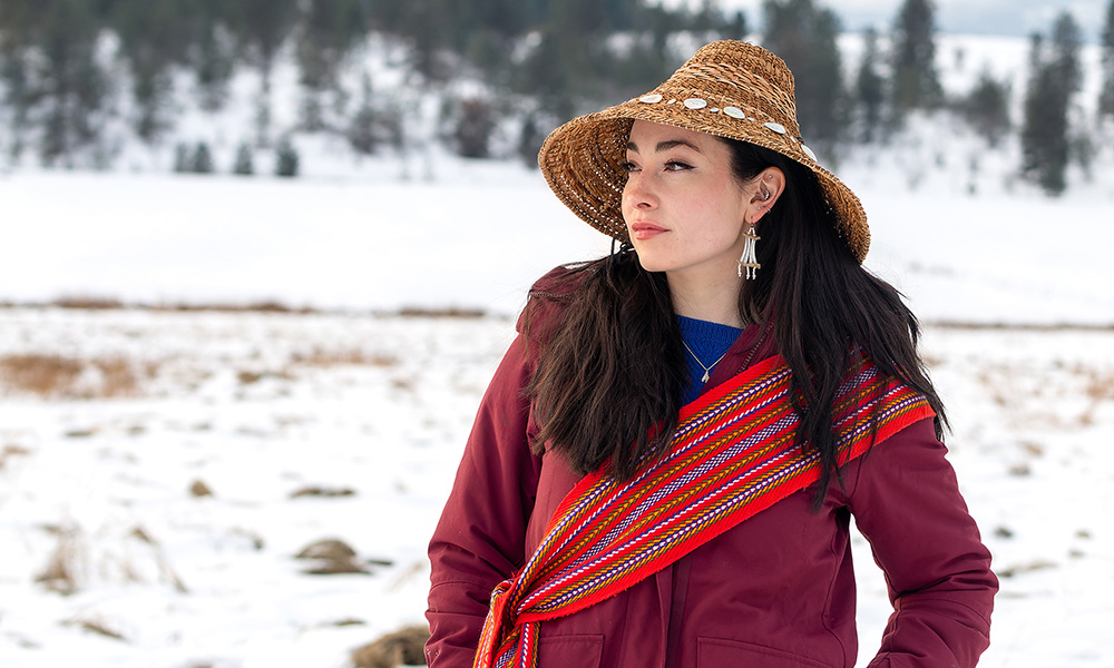 Janna Wale in a traditional Gitxsan sash and hat, against a backdrop of white snow