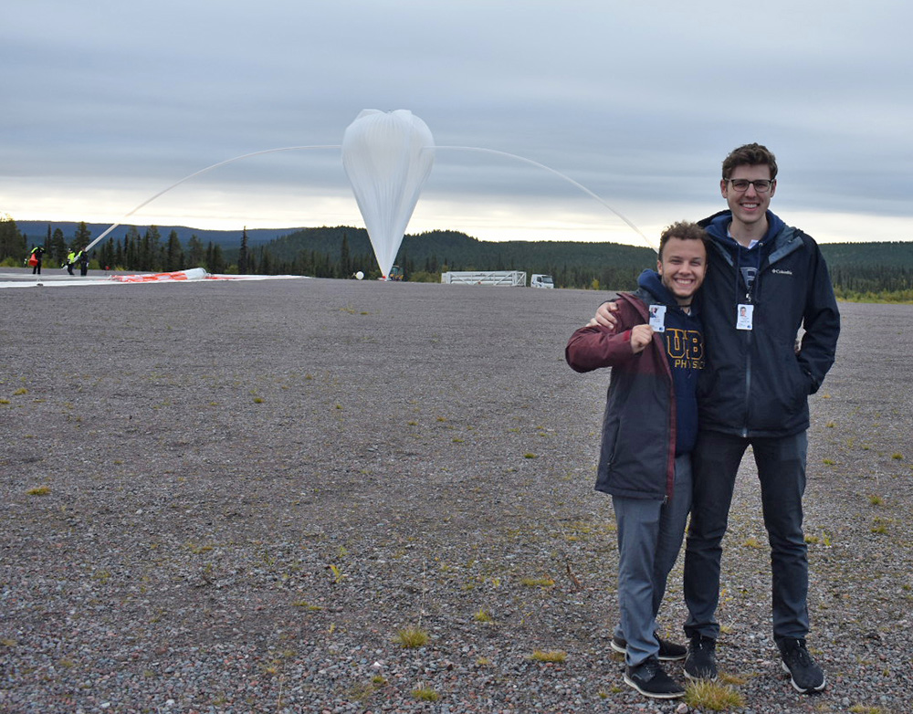 A photo of two students in front of a weather balloon launch