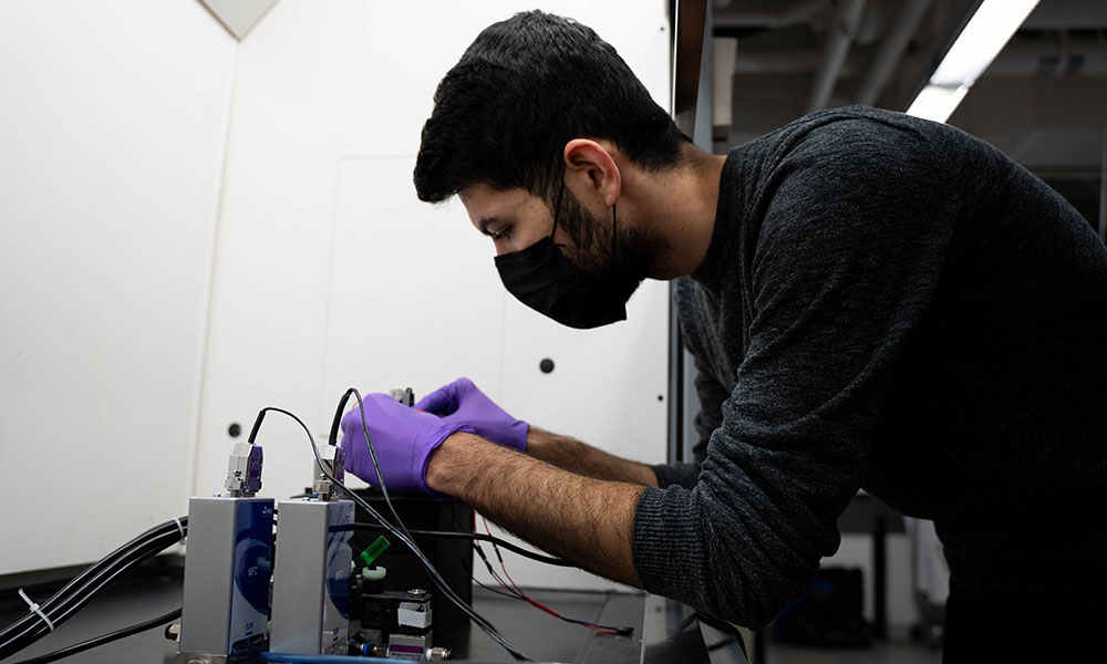 Hamed Mirzaei bending over some small electronics as he adjusts them