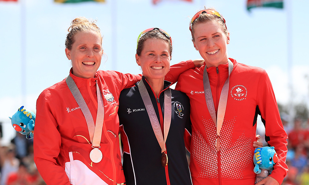 Joanna Brown standing on a podium with two other female athletes - they all have medals around their necks