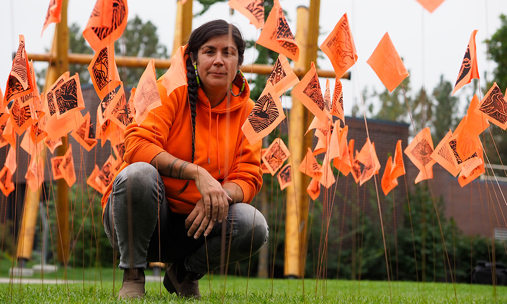 Tania Willard sits amongst hundreds of small orange flags