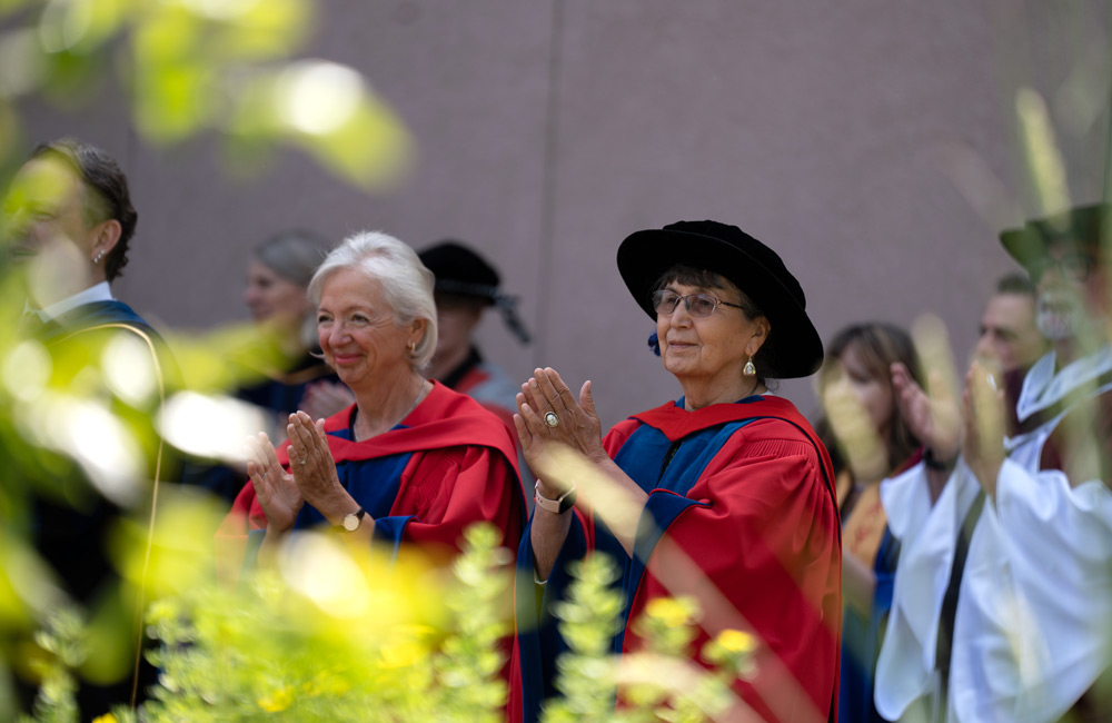 A woman in gradution gown and hat clapping