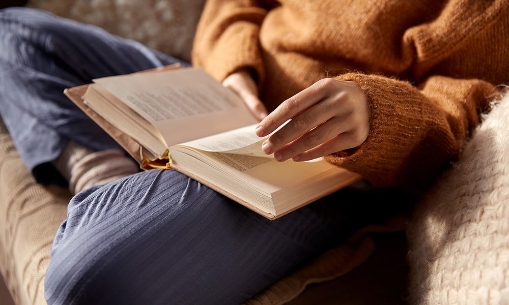 A photo of a woman sitting on the couch reading.