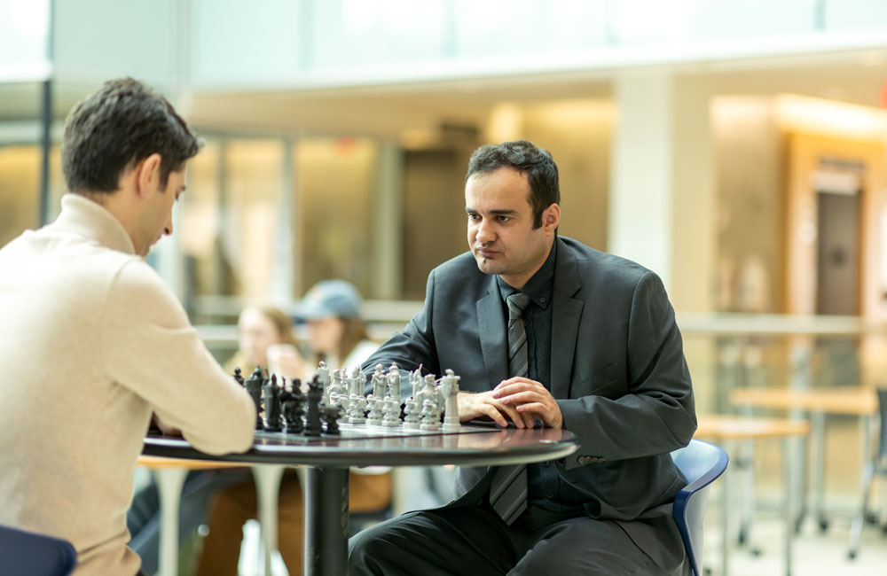 Dr. Amir Adrestani-Jaafari looks at a chess board while considering his next move.