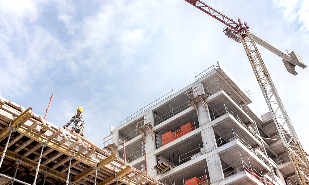 A stock photograph showing a building under construction, with a crane in the background.