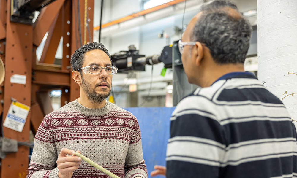 A man is seen talking to Dr. Shahria Alam, holding a piece of plastic-looking rebar in his hands