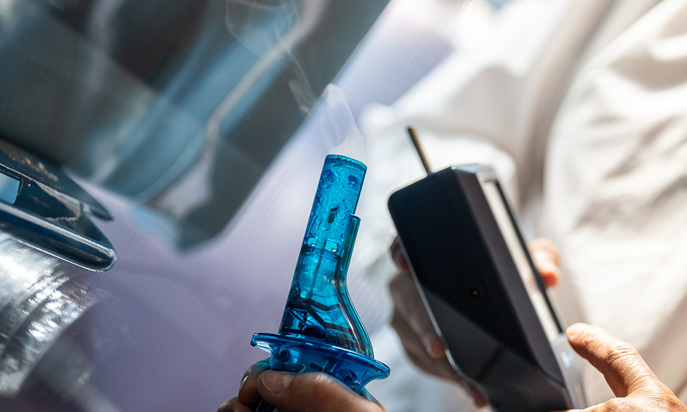 A close-up photo of a carafe with smoke emanating from it, with a particle counter positioned near the smoke.